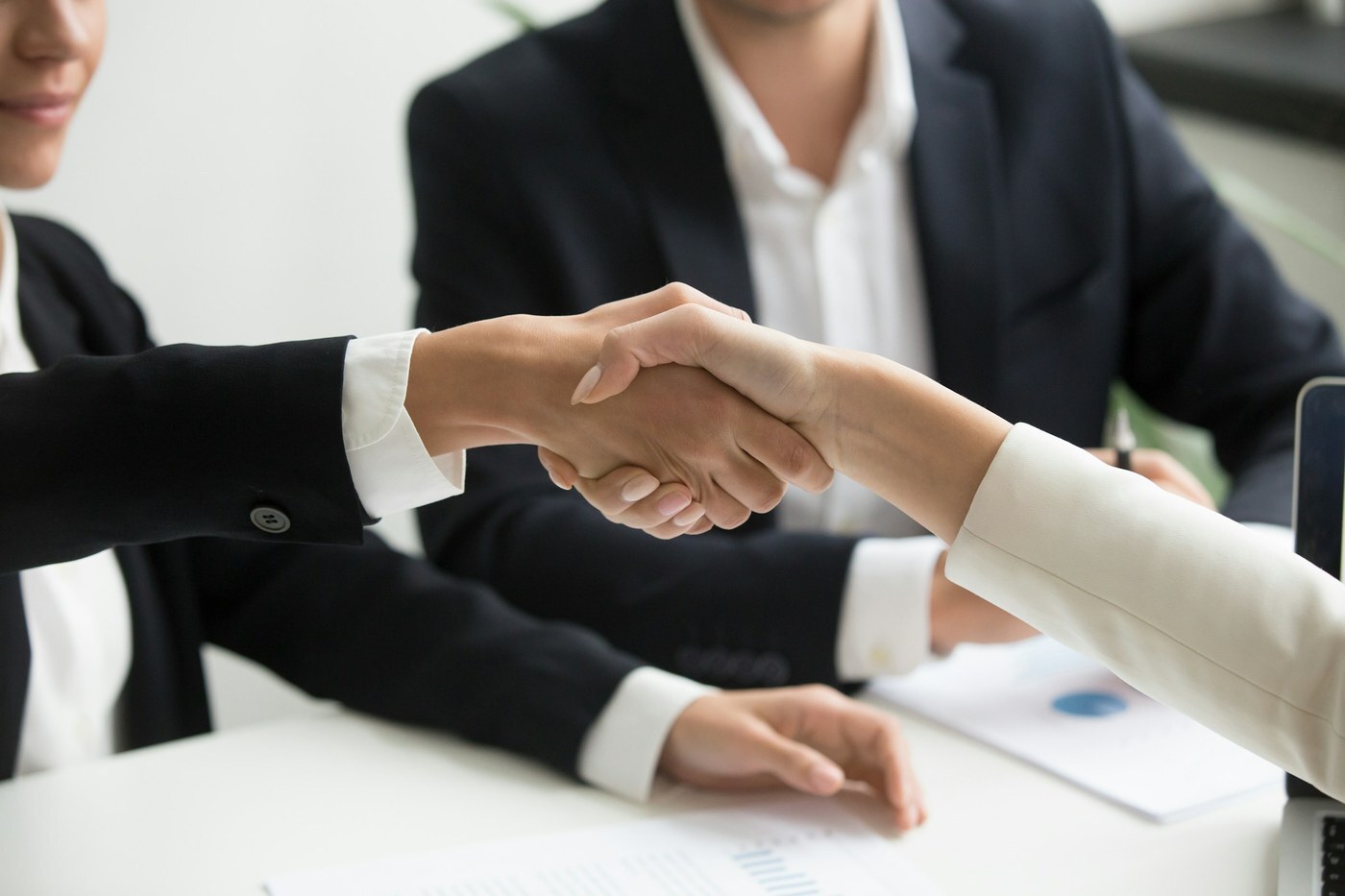 Two business professionals shaking hands across a desk, representing a B2B buyer and seller agreement on Amazon Business