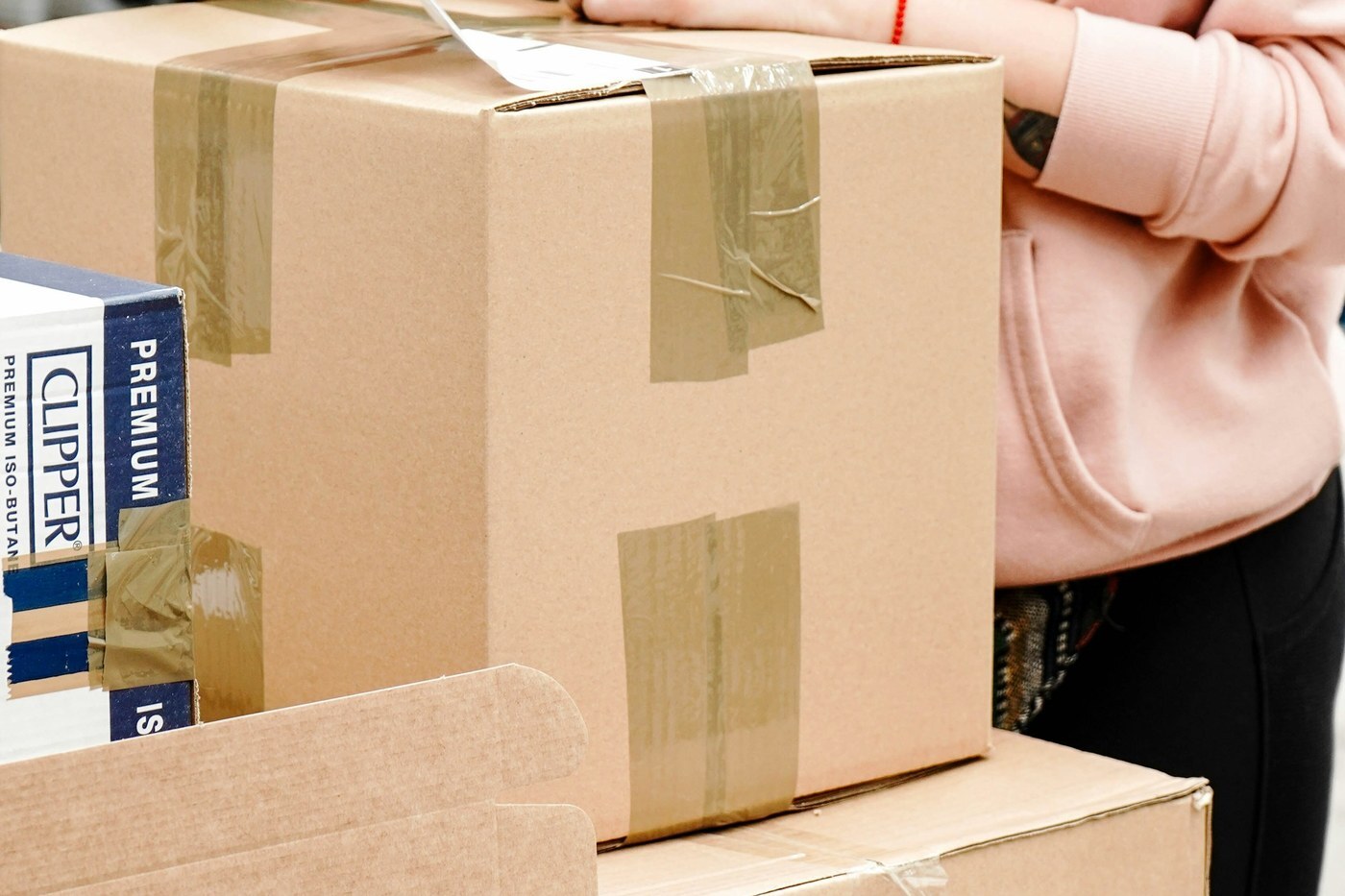 Seller sealing and labeling cardboard shipping cartons on a packing table, the kind of inbound prep used when sending inventory to Amazon Warehousing and Distribution