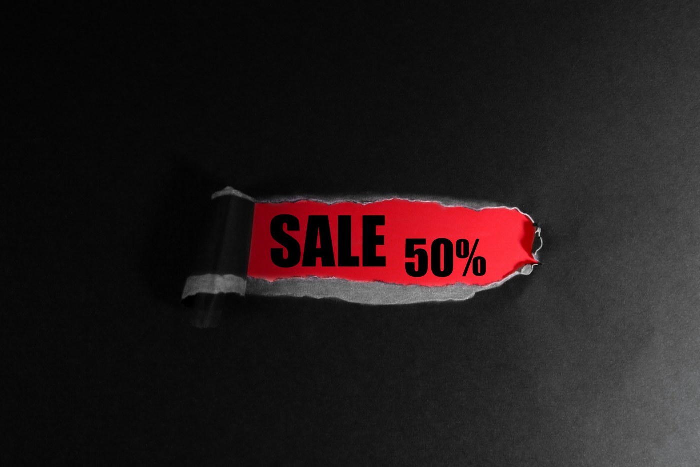 Torn black paper revealing a red sale 50 percent tag, representing the 10 to 50 percent discount range of Amazon Brand Tailored Promotions