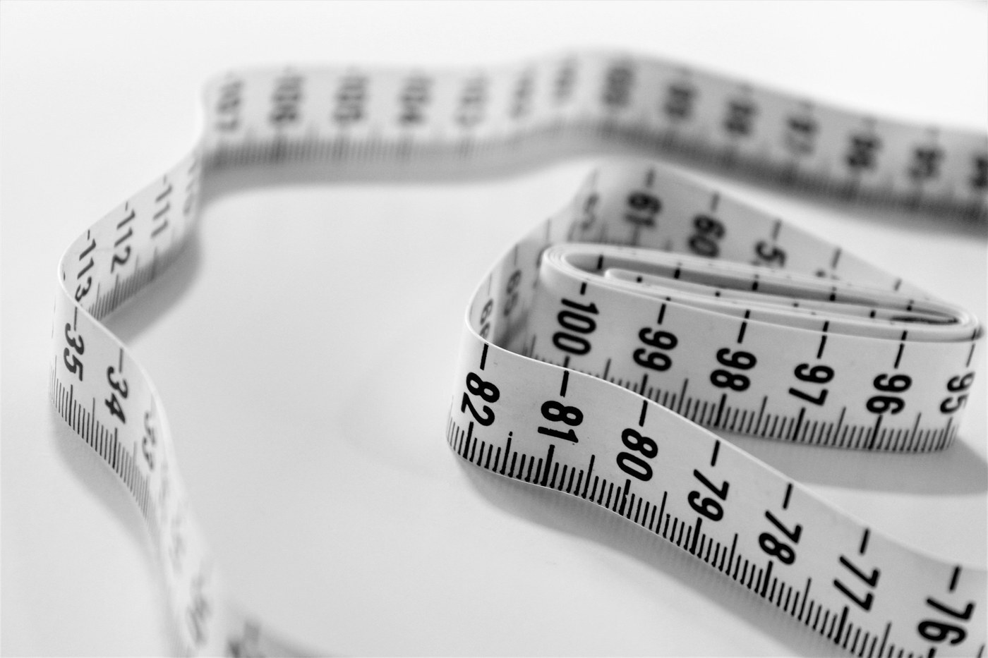 Black and white measuring tape curled on a white surface, representing measuring product dimensions to calculate cubic feet for Amazon FBA capacity limits