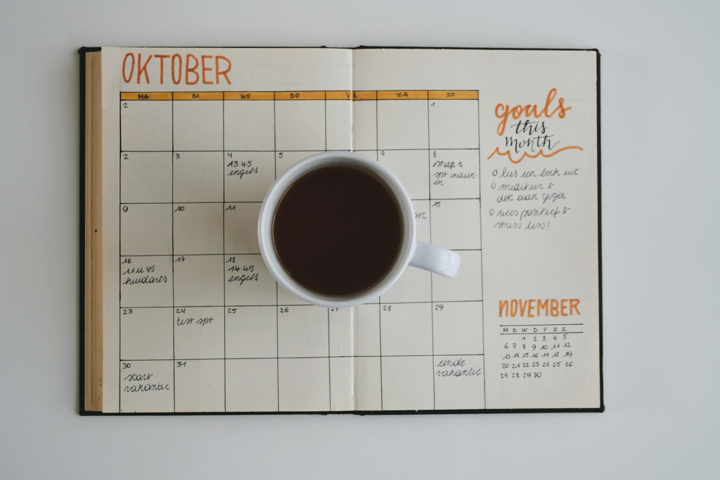 Open monthly planner showing October with handwritten notes and a cup of black coffee, representing planning Amazon FBA inbound deadlines for Black Friday and Cyber Monday 2026