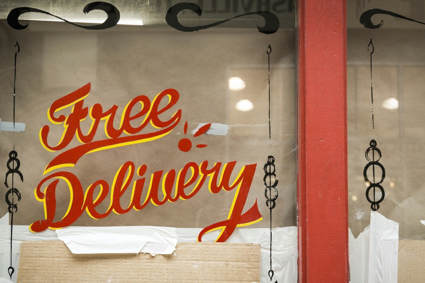 Hand-painted Free Delivery sign in red and yellow lettering on a shop window, representing free and fast shipping as a factor in winning the Amazon Featured Offer