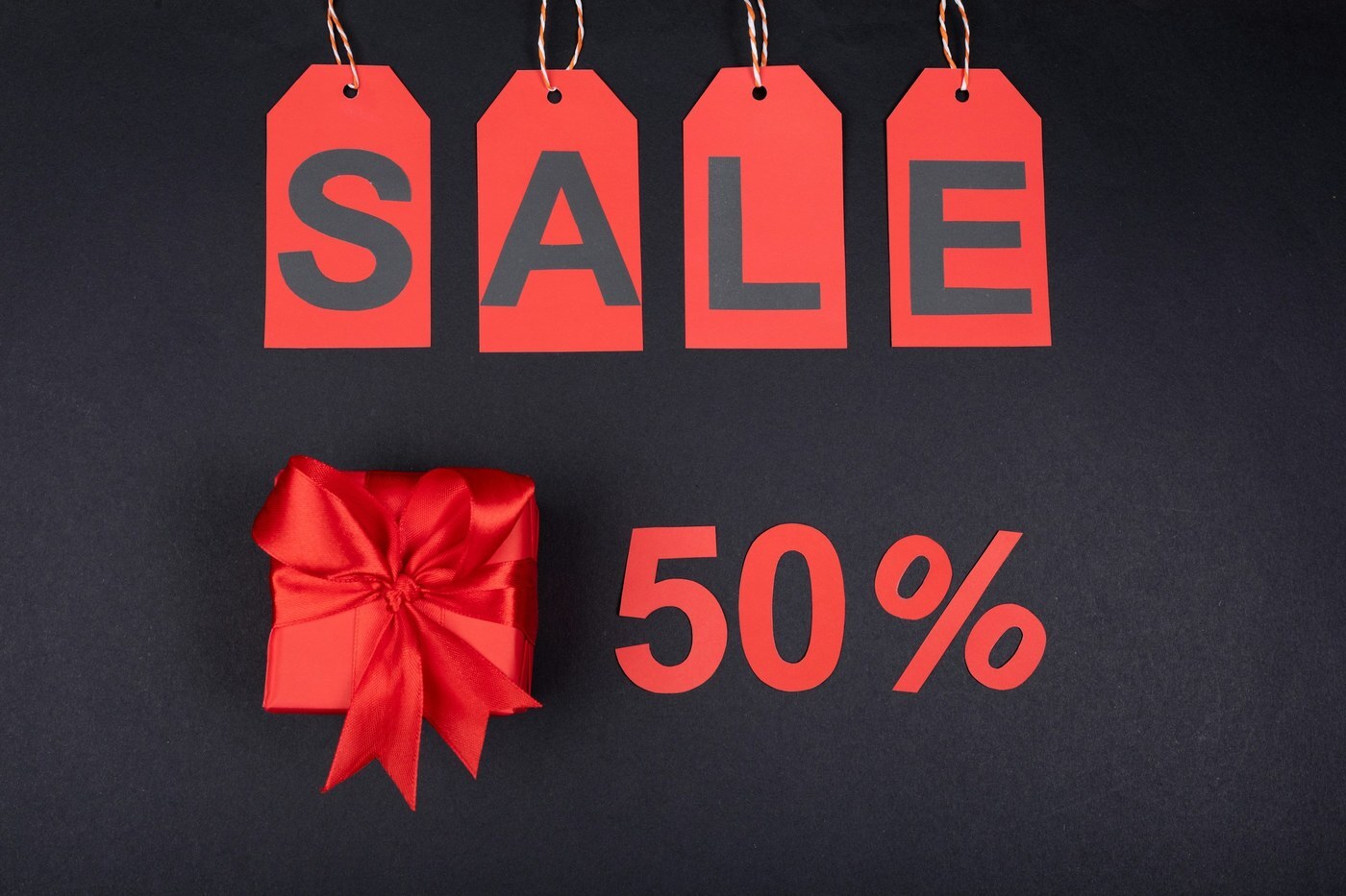 Red SALE tags and 50 percent off cutouts with a wrapped gift box, representing Black Friday Week and Cyber Monday promotions on Amazon