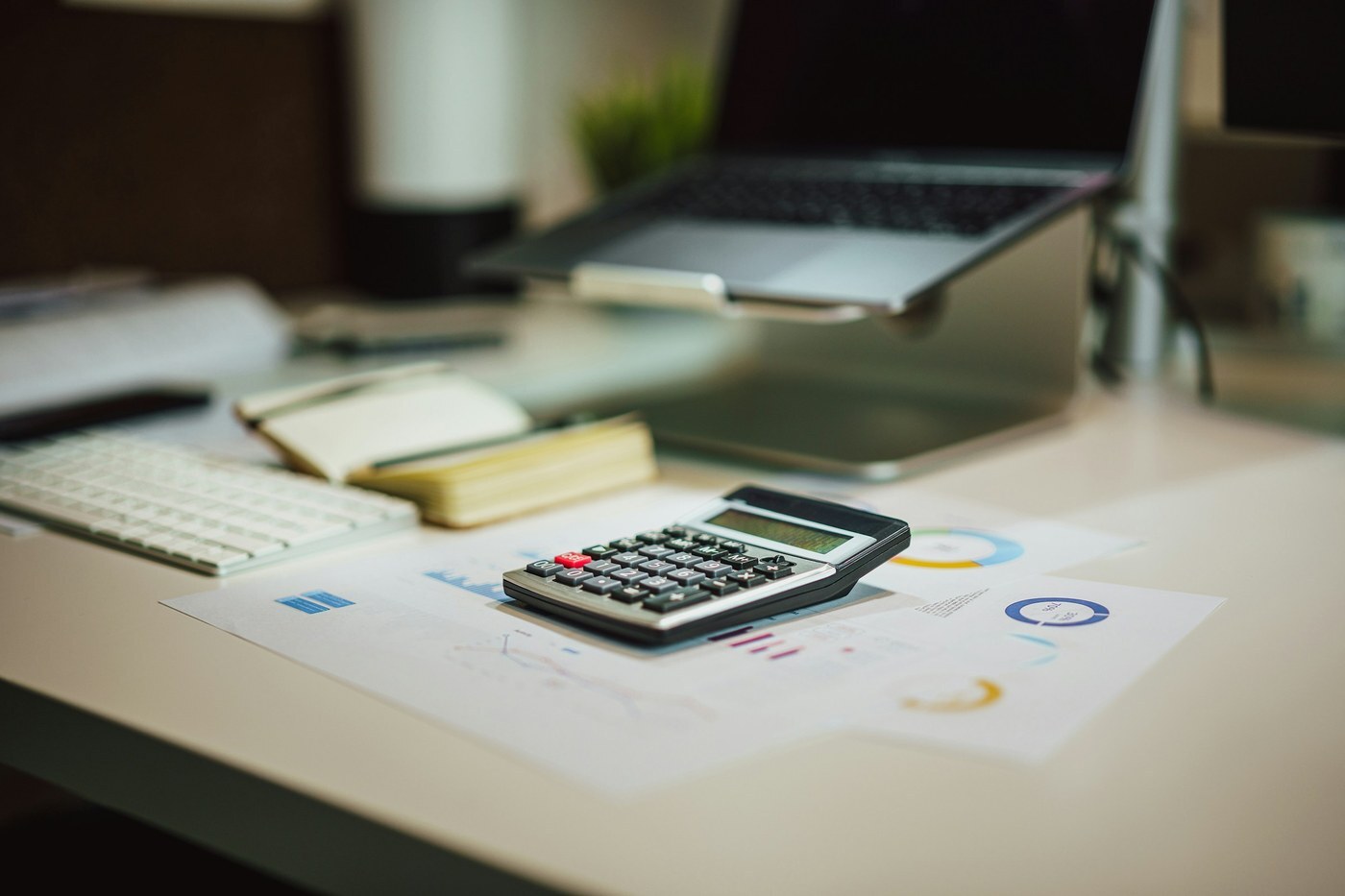 Calculator on printed charts next to a laptop, representing the math behind Amazon MCF fulfillment fees