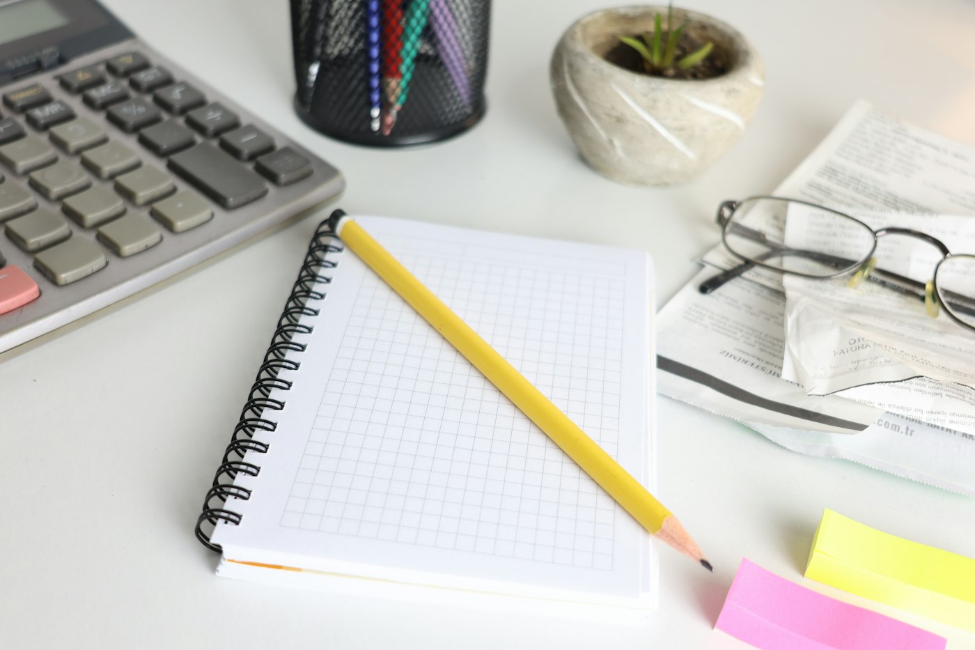 Desk with a calculator, notebook, and pencil for planning Amazon promotion costs and margins