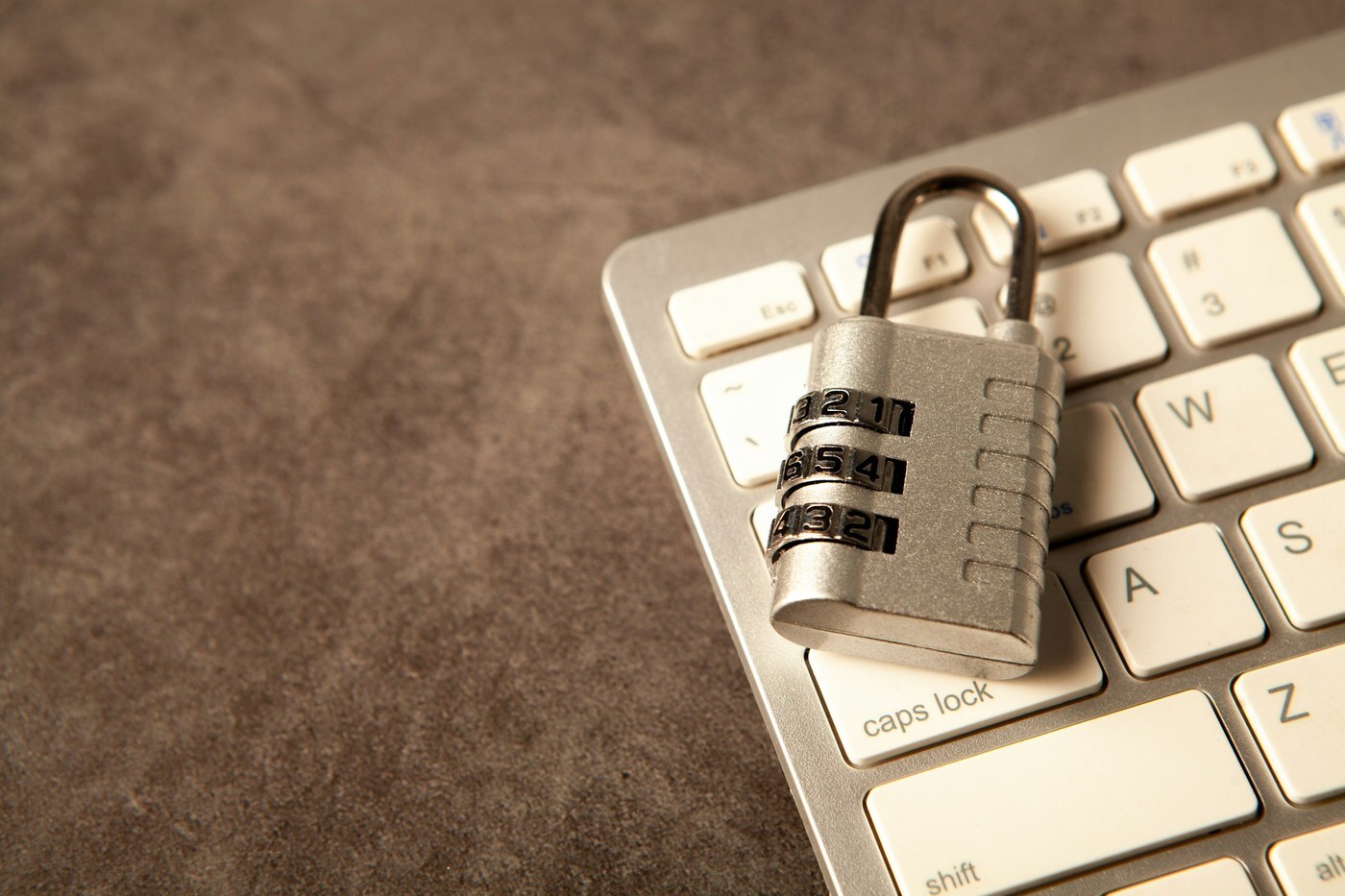 Silver combination padlock resting on a white computer keyboard, representing protecting your Seller Central data before connecting an outside AI assistant