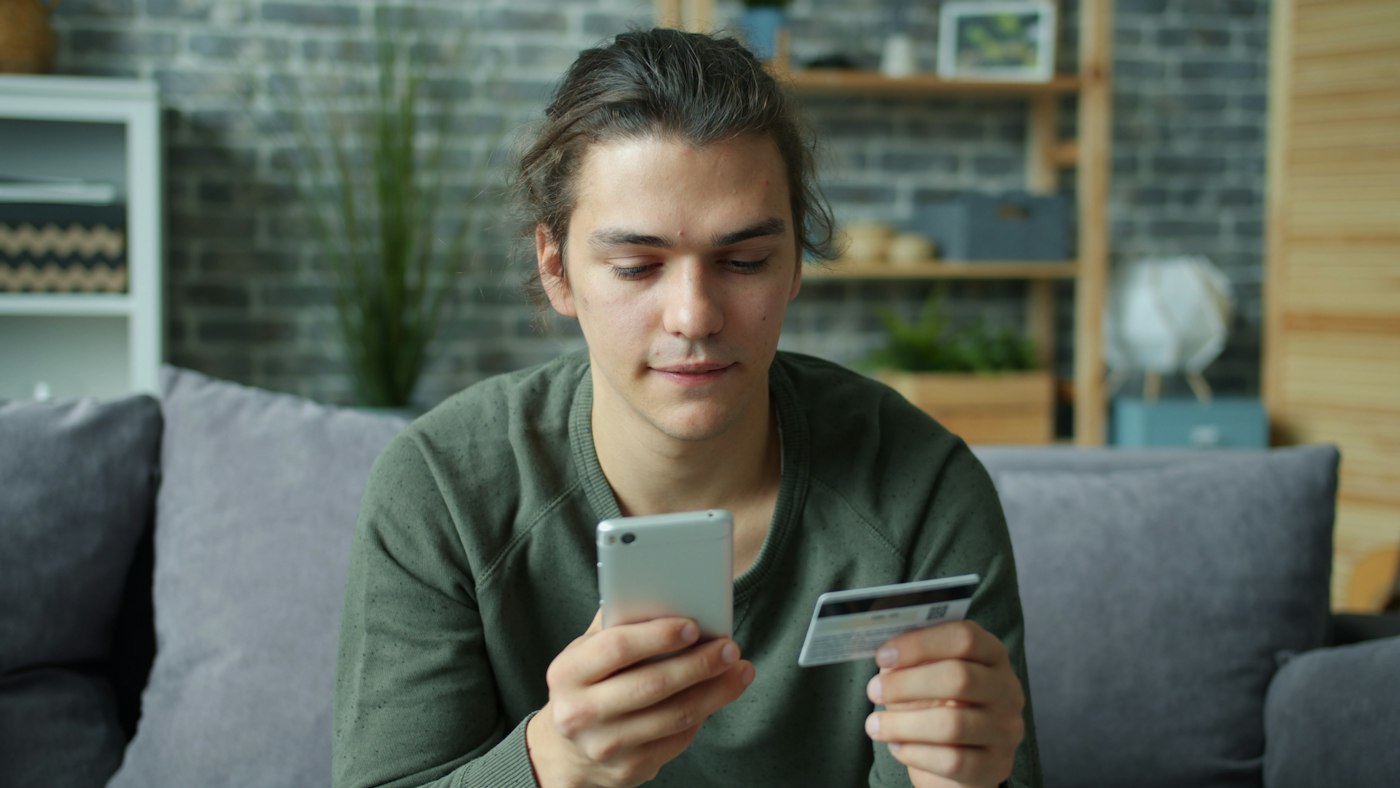 Online shopper holding a smartphone and credit card while checking a discounted product