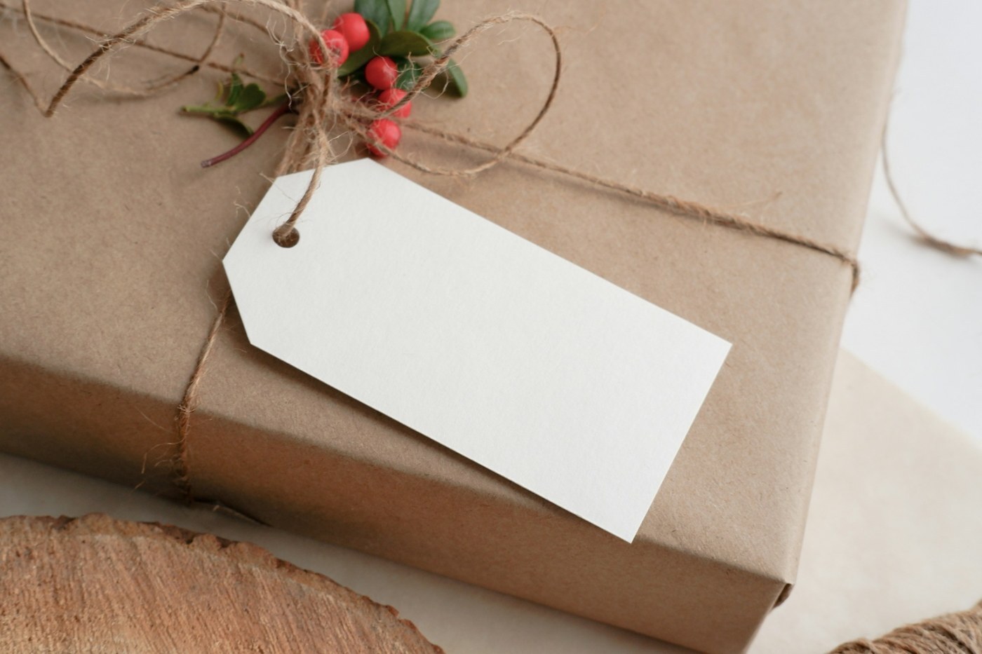 Gift wrapped in kraft paper and twine with a blank white tag and red berries, representing personalized Amazon Brand Tailored Promotions for loyal customers