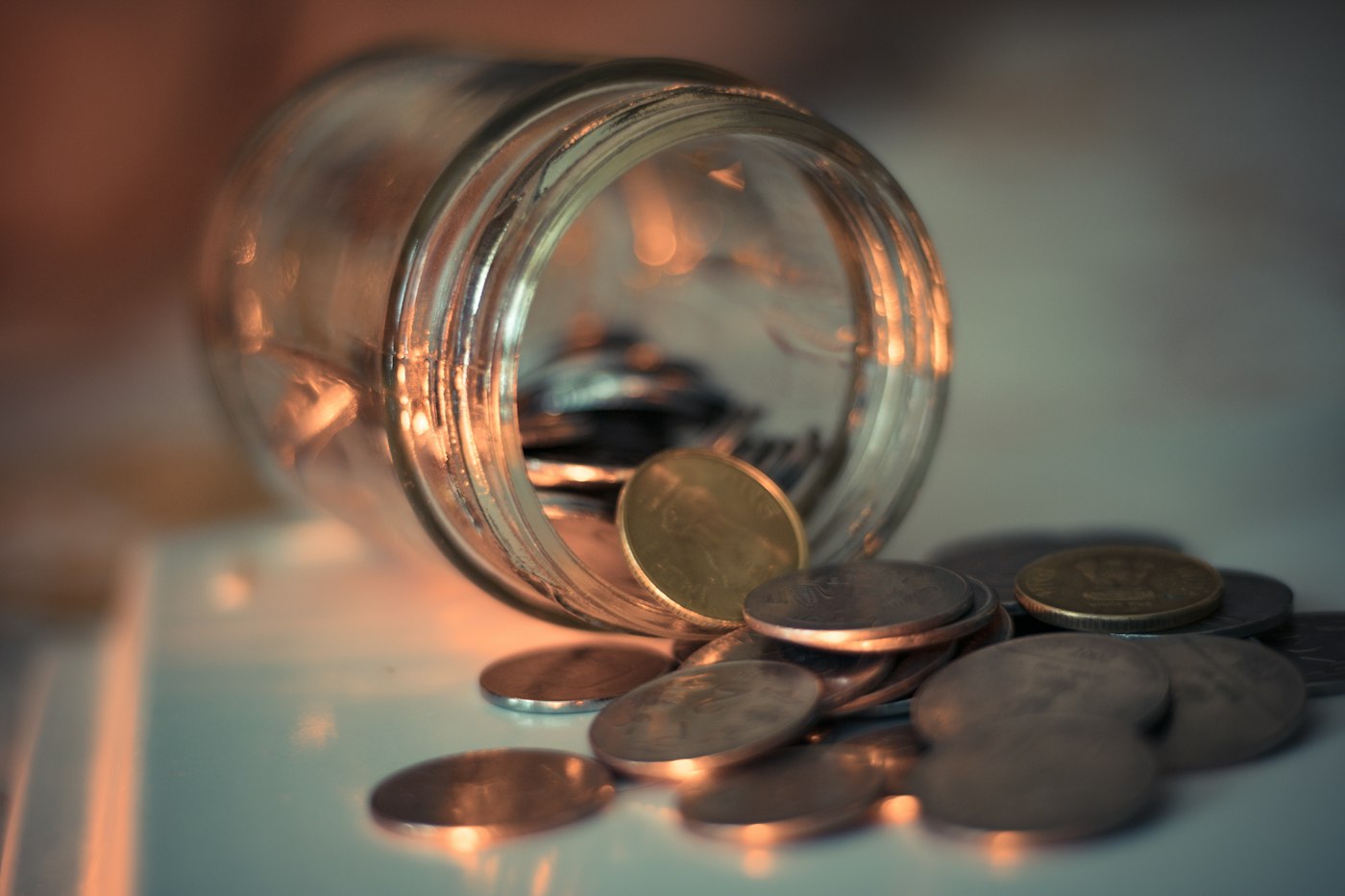 Tipped glass jar spilling coins, representing money recovered through Amazon FBA reimbursements
